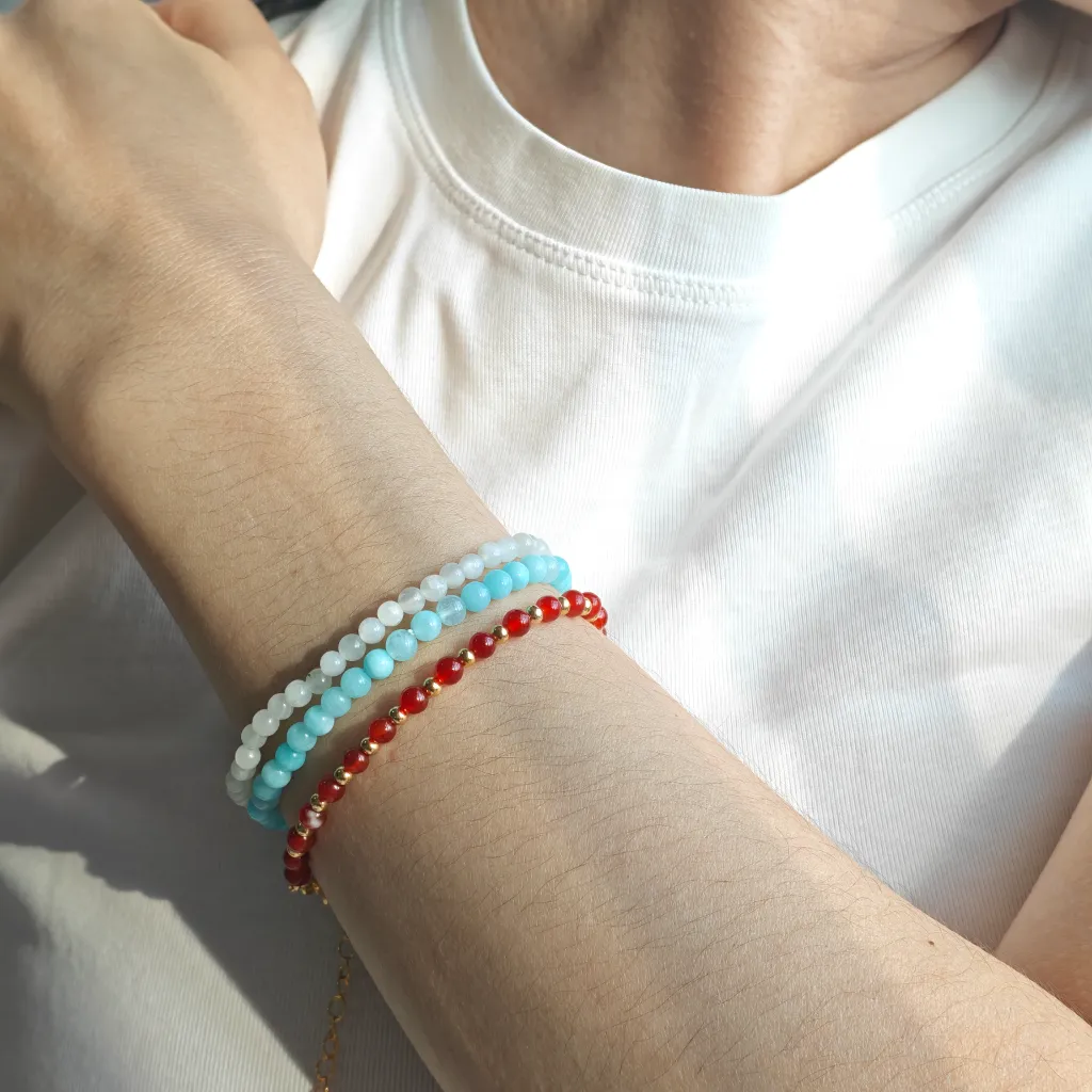 Aquamarine bracelet layered with White Agate Bracelet and Carnelian bracelet on the wrist — a stacked everyday styling